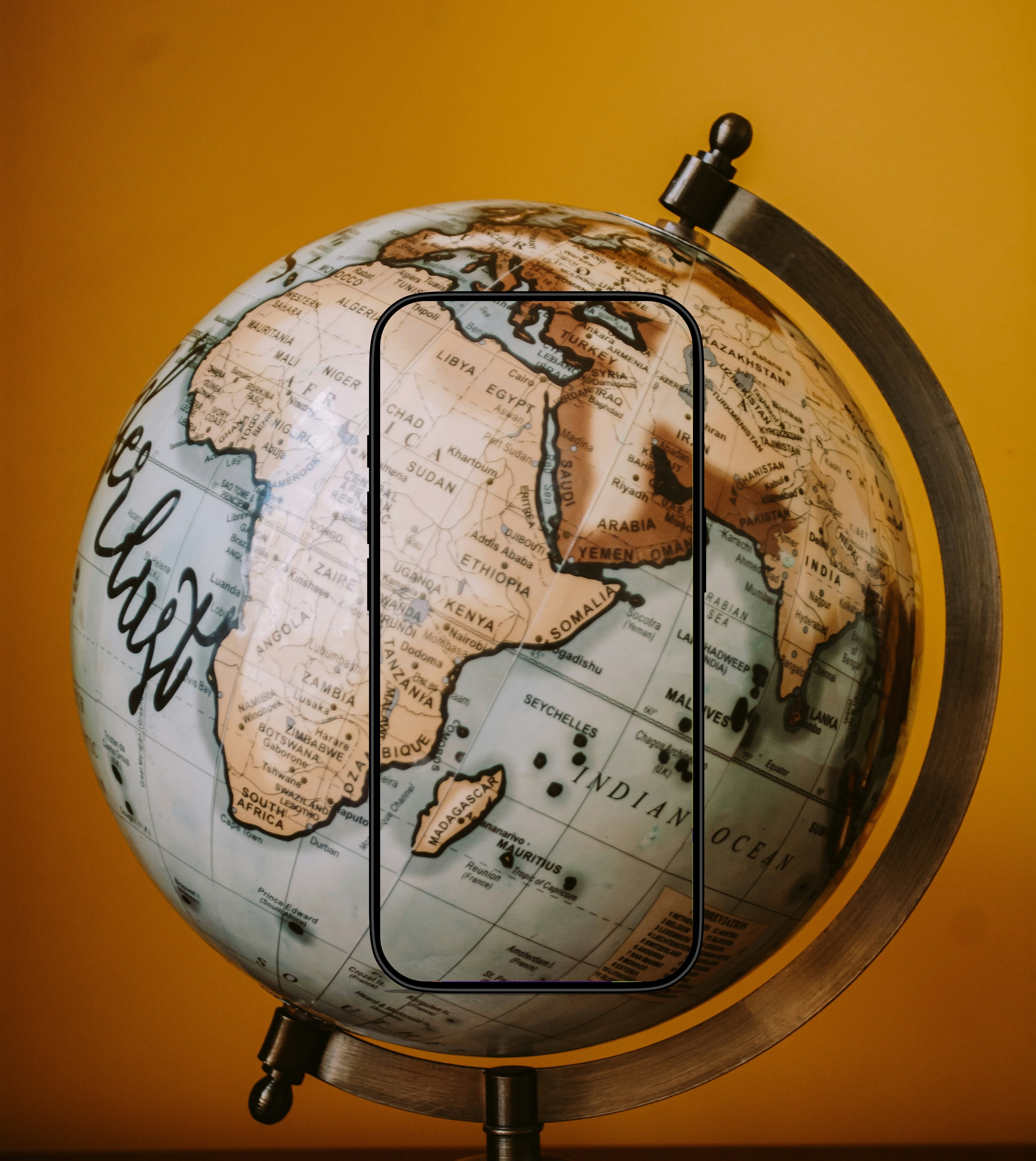 Phone displaying PhotoMaps app in front of a world globe